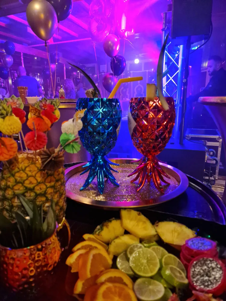 Kleurrijke ananasbekers en vers gesneden fruit bij een feestelijke cocktailopstelling